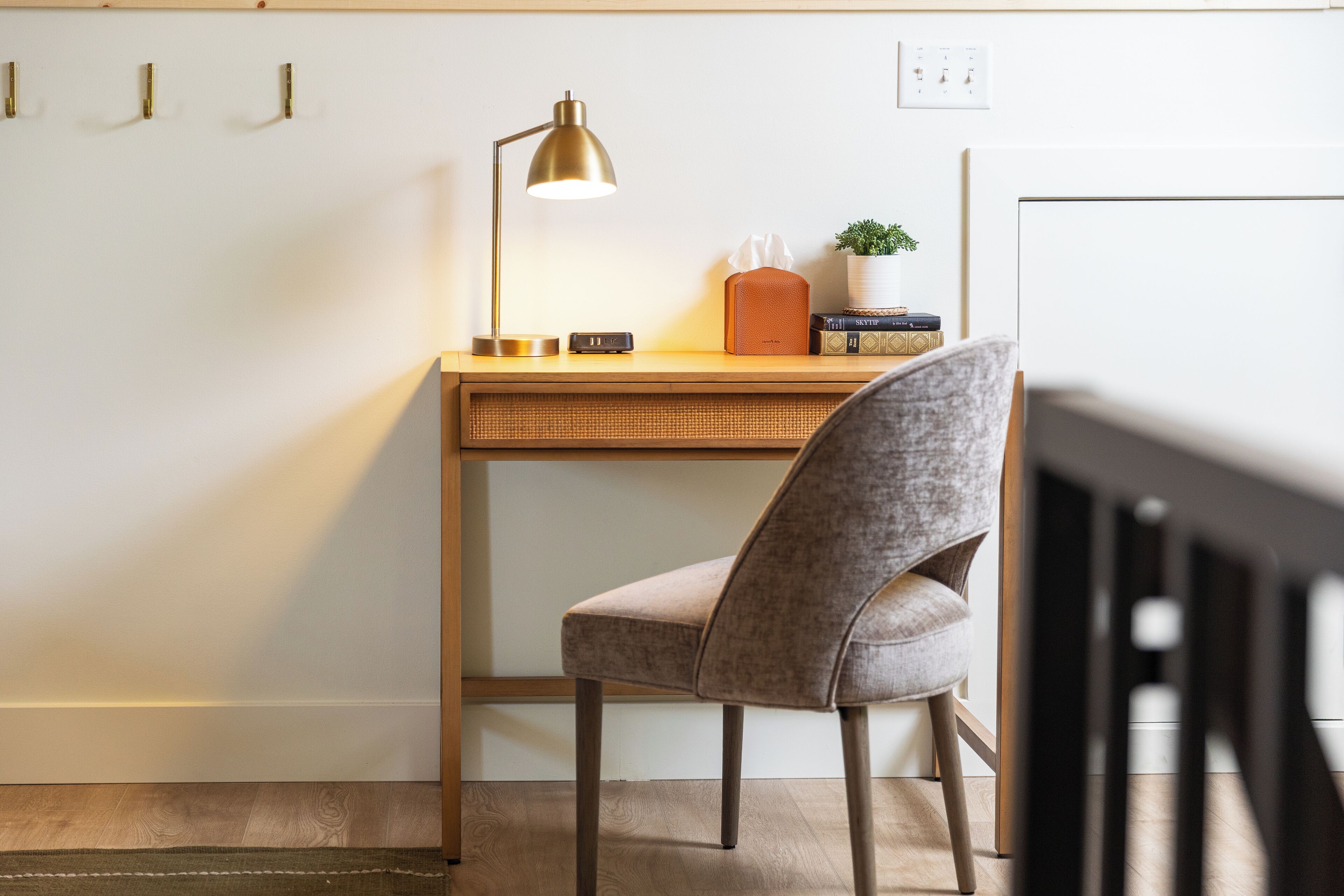 A workspace with a desk, chair, lamp, and a small potted plant.