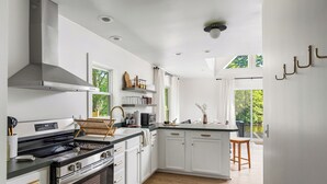 Eine moderne Küche mit weißen Schränken, einer Edelstahl-Dunstabzugshaube und Holzboden.