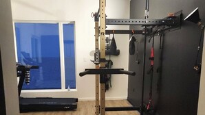 A home gym with a pull-up bar, weight rack, and exercise equipment.