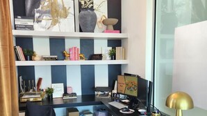 A modern office with a desk, chair, and shelves with books and decorative items.