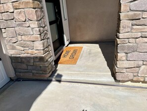 A stone exterior wall, a door with a doormat, and a concrete floor. - Luxury 3,000 sq. ft. Single-Story Home in a Premier Clovis Neighborhood (Clovis)