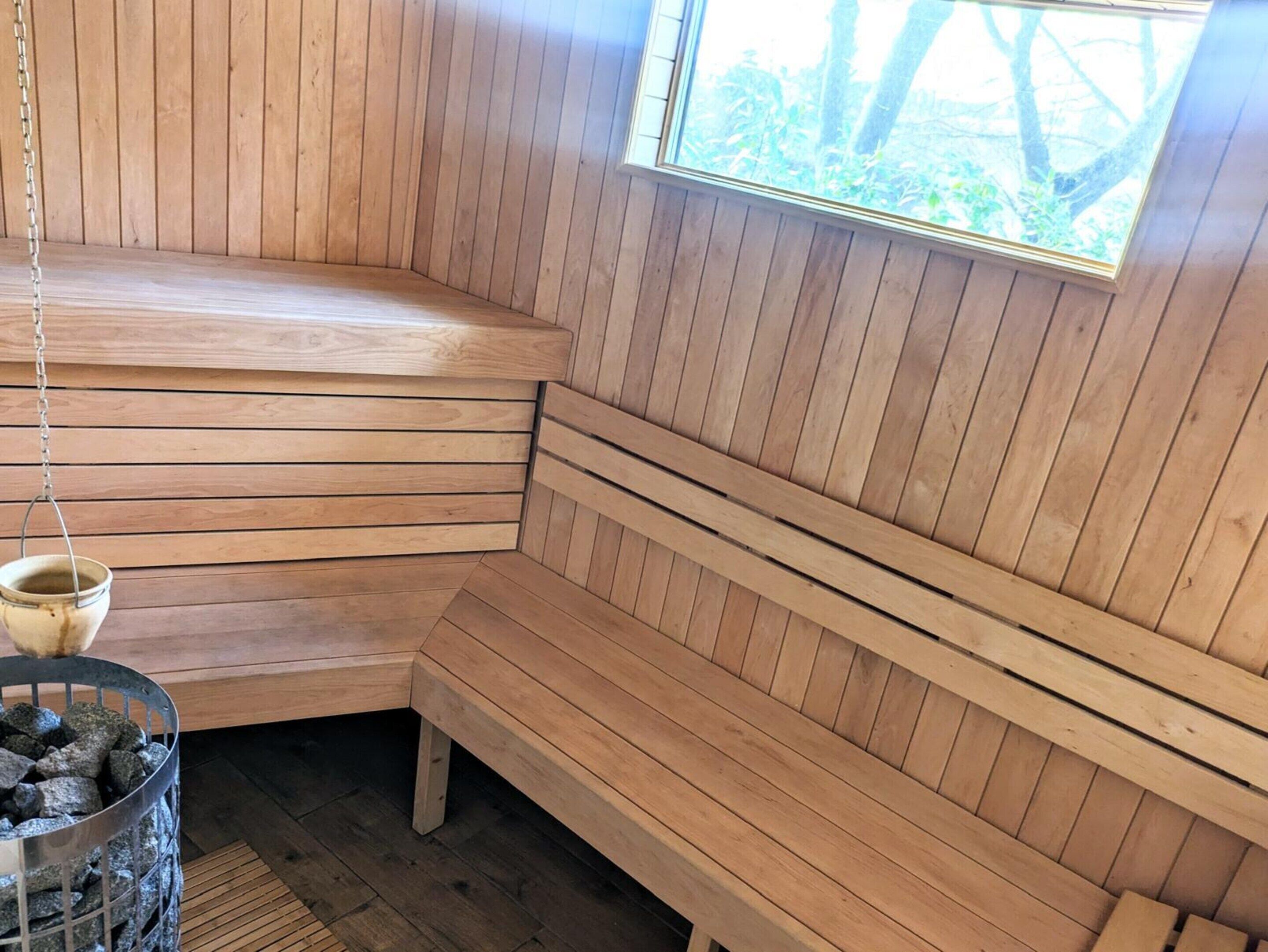 Een houten sauna met banken en een raam.
