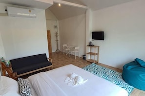 A hotel room with a bed, a sofa, a TV, and a desk.