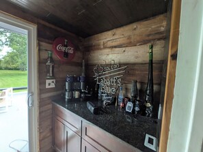 A wooden interior with a bar area featuring a Coca-Cola sign, a Toledo sign, and a Bartles Blue sign.