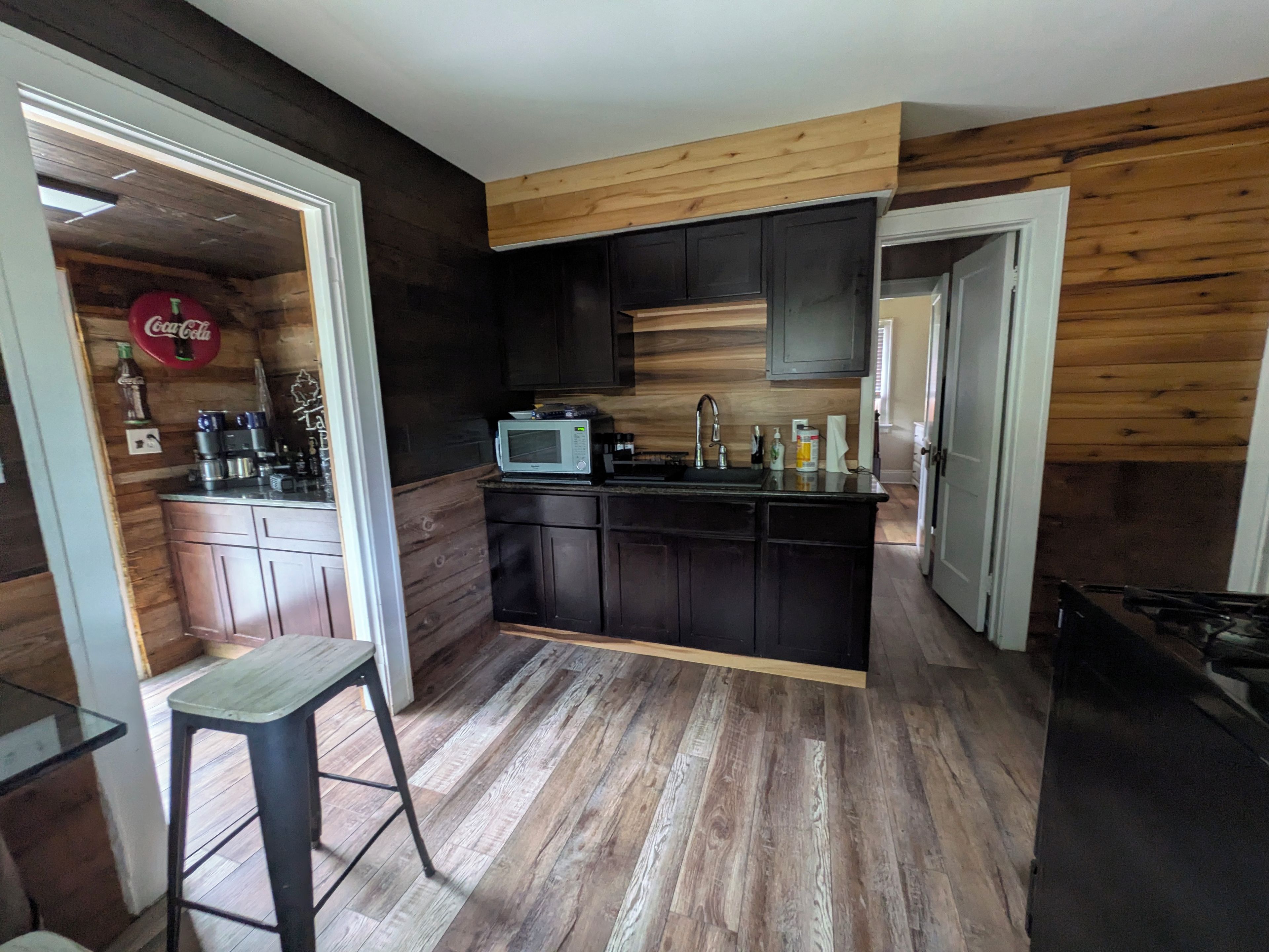 Cocina compacta con armarios de madera oscura, encimera de madera, microondas y lavabo.