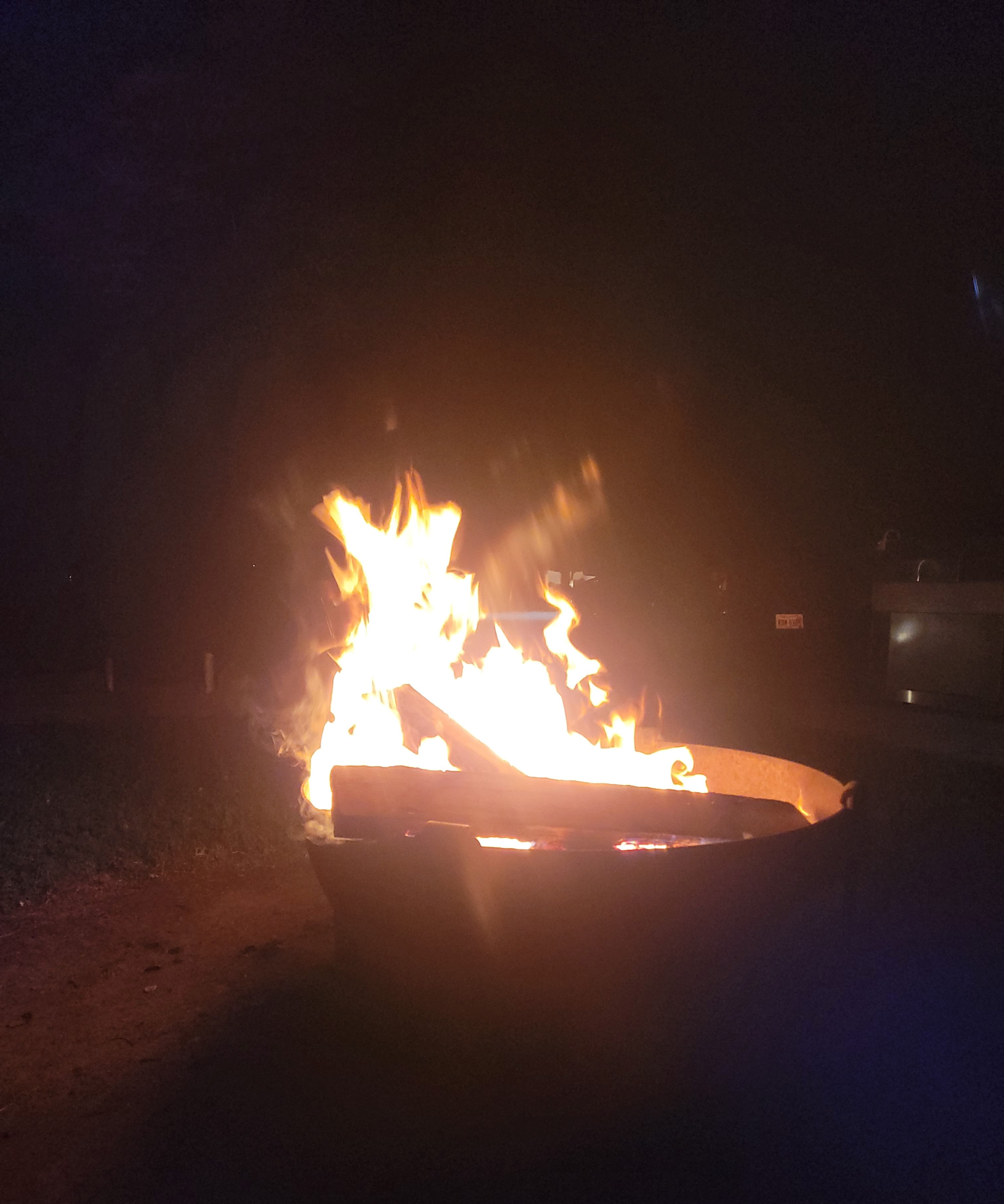 Un foc cremant en un recipient metàl·lic durant la nit.