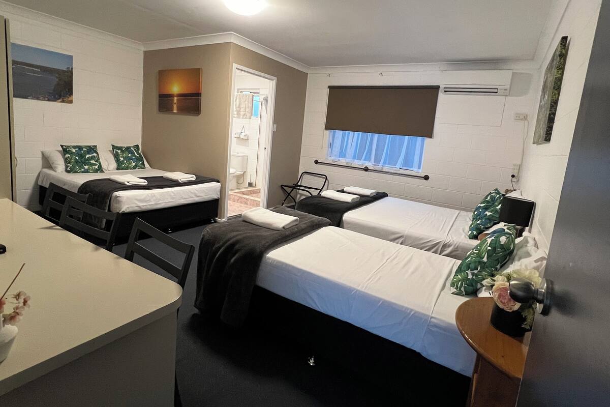 A compact hotel room with two single beds, a small desk, and a chair.