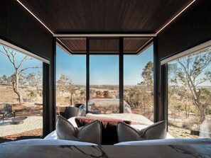 Un dormitorio con un ventanal que ofrece vistas a un paisaje árido.