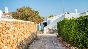 A stone pathway leading to a building with a white facade and a staircase. - Can Carnero | House in Menorca with sea views (Cap D'Artruix (Ciutadella De Menorca))
