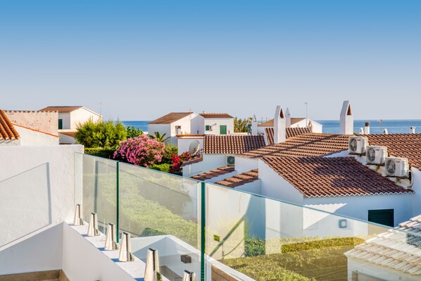 Un área residencial costera con tejados de tejas de arcilla, paredes blancas y una vista despejada del mar.