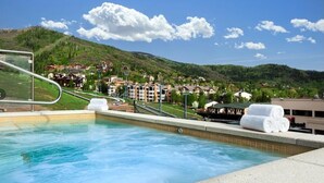 Ein Schwimmbecken mit Blick auf ein Hügel-Dorf und einen Berg im Hintergrund.