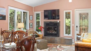 Ein Wohnzimmer mit Kamin, Fernseher und Essbereich mit Stühlen und Tisch.