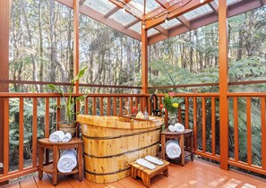 A wooden hot tub with towels and a small table, surrounded by a wooden deck with railings, and a glass ceiling. - Liko Lehua Cottage in Volcano - Hot Tub & Fireplace - Mauna Loa Estates (Volcano)