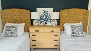 Een slaapkamer met twee bedden, een houten dressoir en een donkere muur.