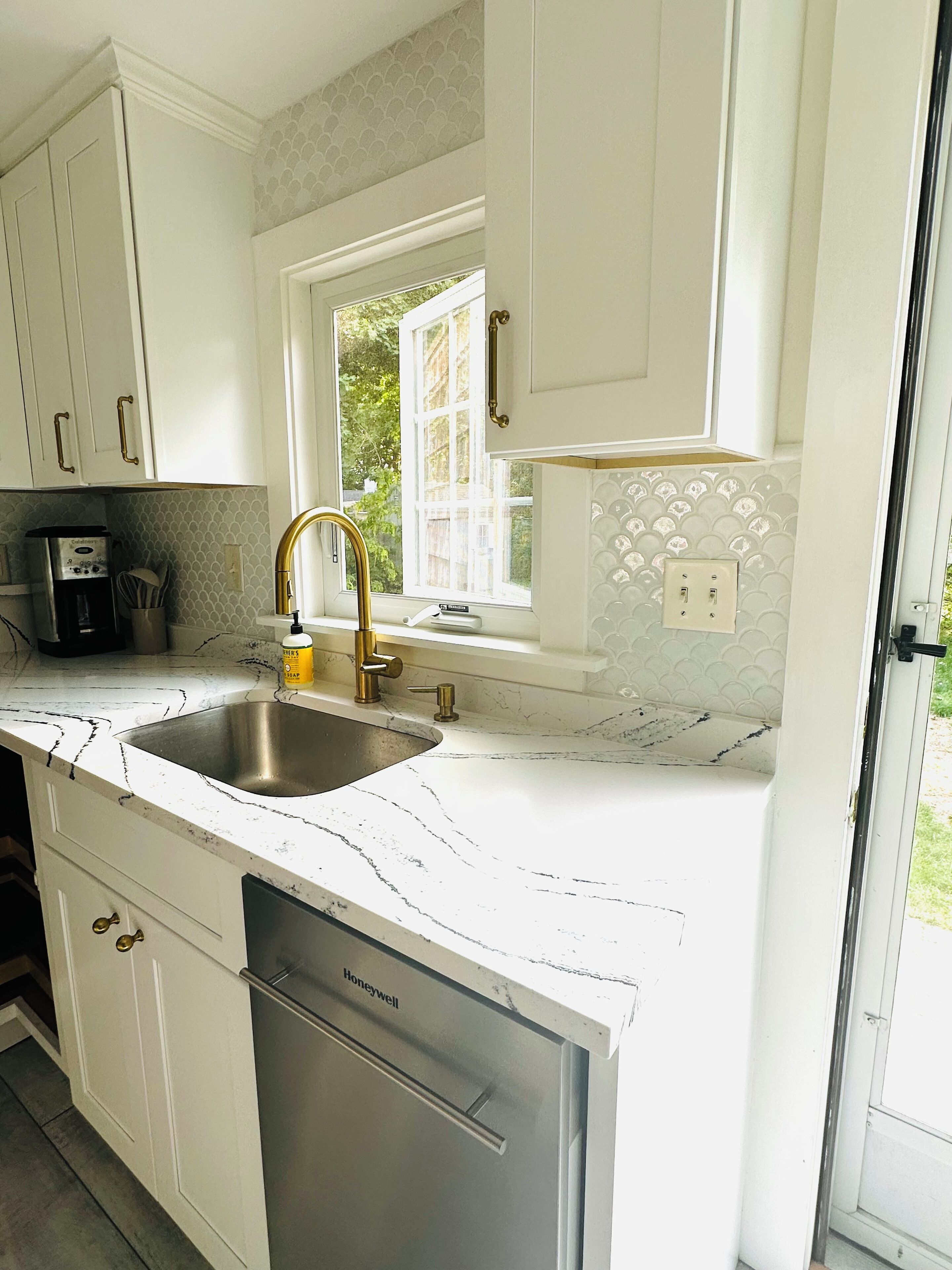 A kitchen with white cabinets, a stainless steel sink, and a built-in dishwasher.