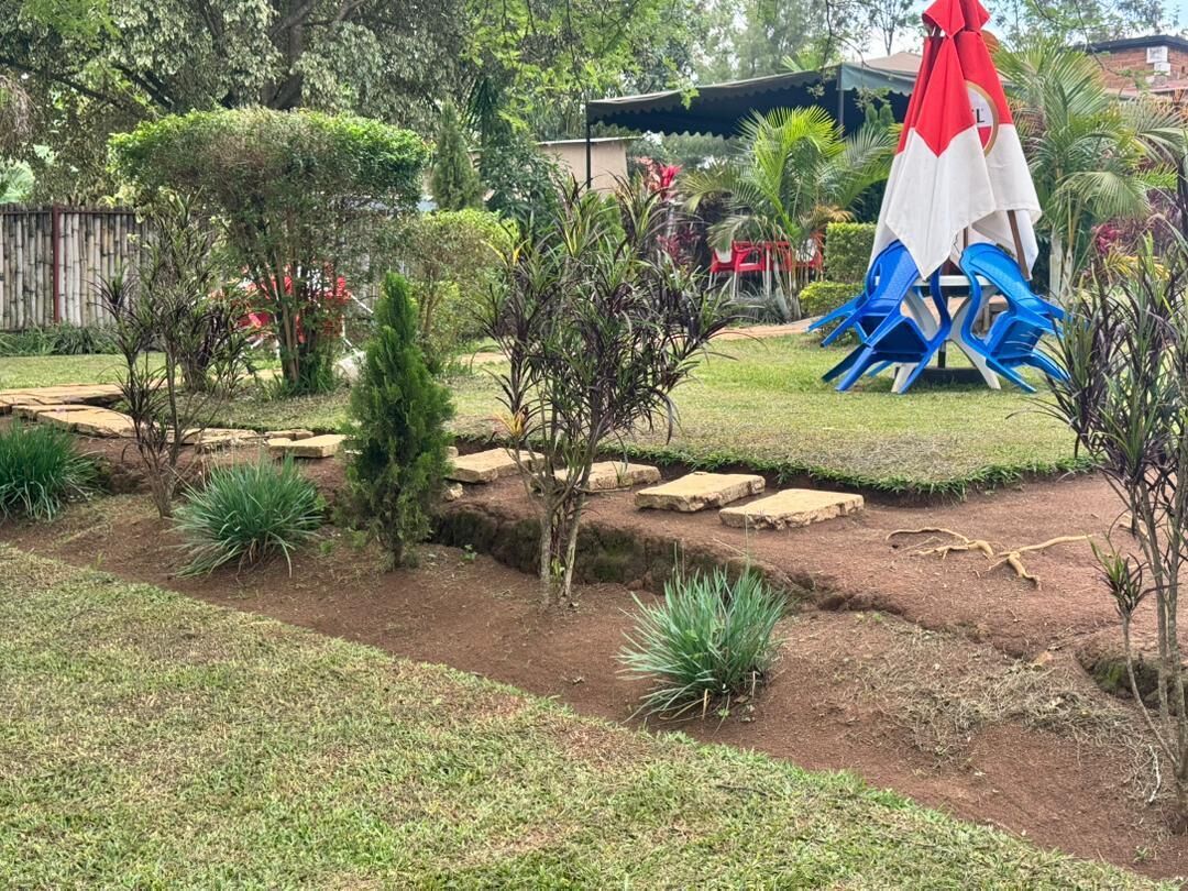 A garden with a small pond, stepping stones, and a red and white umbrella.