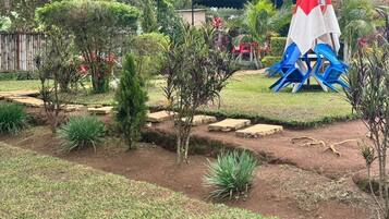 A garden with a small pond, stepping stones, and a red and white umbrella.
