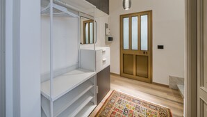 Ein moderner Flur mit Kleiderschrank, Spiegel, einer Tür mit Milchglasfüllung und einem gemusterten Teppich.