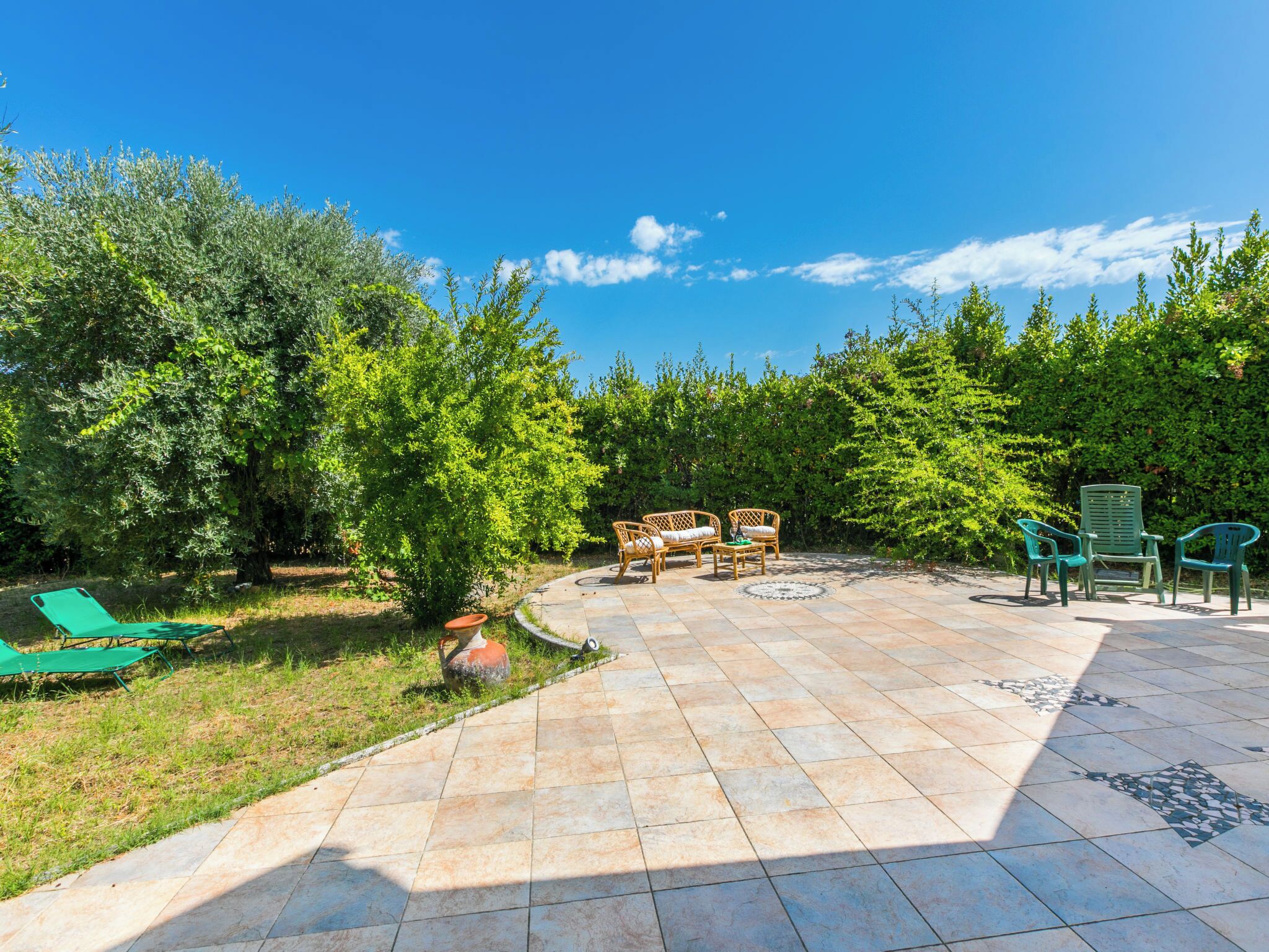 An outdoor patio area with a tiled floor, a small round table, and two wicker chairs.