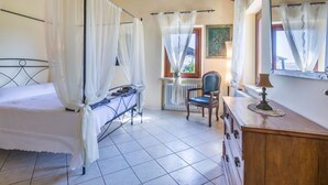 A bedroom with a bed, a chair, a dresser, and a window with curtains.
