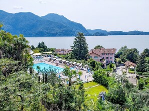 Un complexe hôtelier doté d’une piscine, de chaises longues et offrant une vue sur un lac et des montagnes.