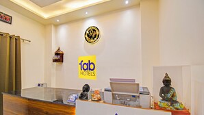 A hotel reception area with a wooden reception desk, a Buddha statue, and a clock on the wall. - Fabhotel Rj (Patna)