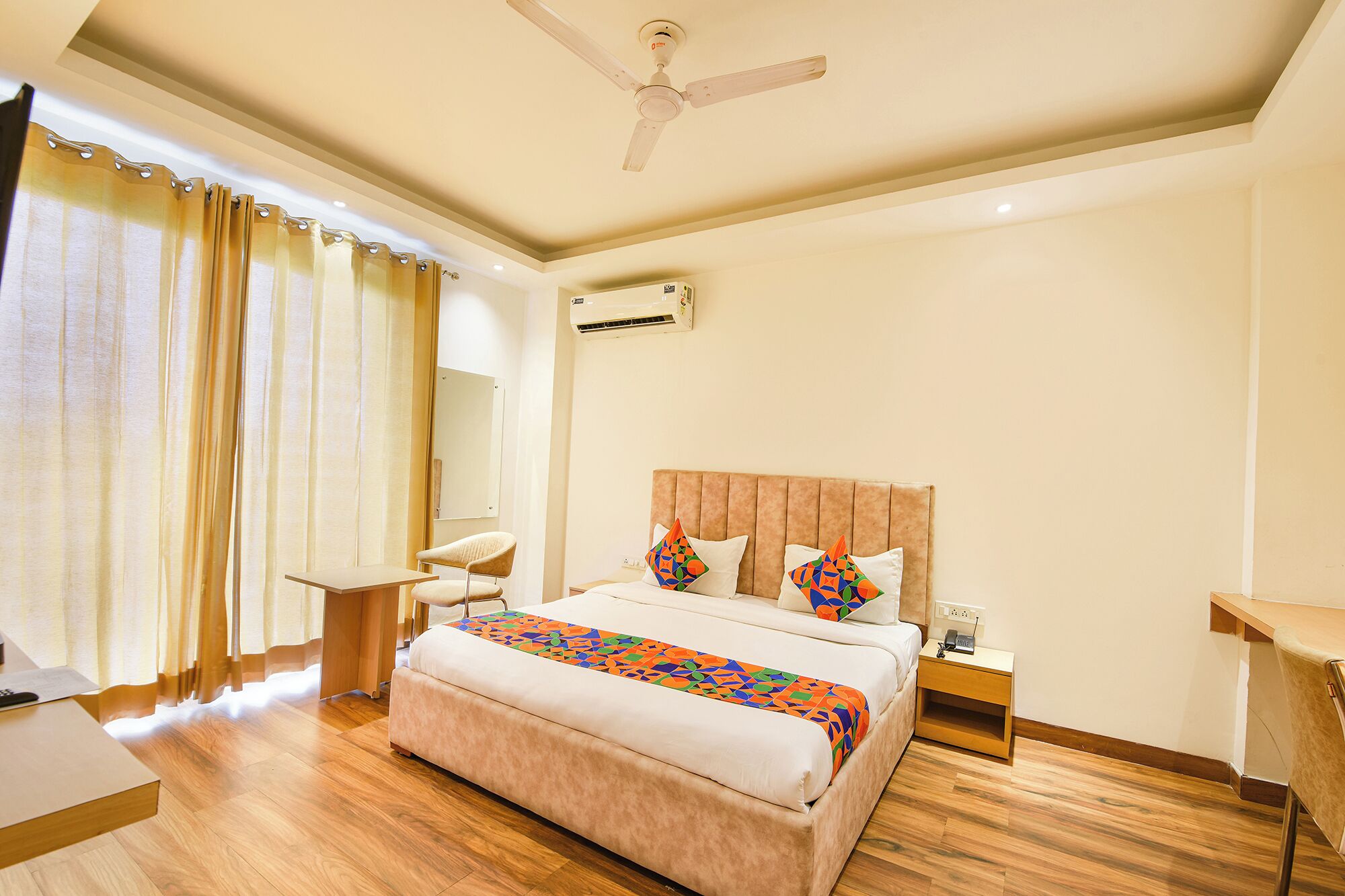 Une chambre d’hôtel équipée d’un lit, d’une table de chevet, d’une chaise et d’un ventilateur de plafond.