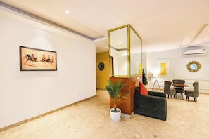 A modern lobby with a large mirror, a framed horse painting, a potted plant, and a seating area with a table and chairs. - Fabhotel The Prime Land (Gurugram)
