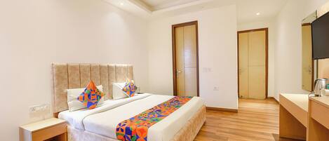 A bedroom with a bed, nightstand, wooden floor, and a bathroom door.