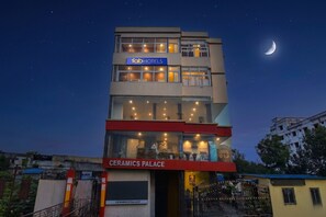 Un hotel llamado 'fabHOTELS' con un letrero sobre la entrada, una luna grande en el cielo y un edificio de fachada roja y blanca.