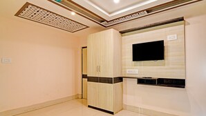 Una habitación con armario, televisor de pantalla plana en la pared y diseño de techo empotrado.