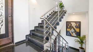 A modern staircase with a metal railing, a potted plant, and a framed abstract artwork on the wall. - Fabhotel Komfort Inn (Pune)