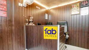 A reception desk with a 'fab hotels' sign, a statue, and a digital clock displaying the time. - Fabhotel Komfort Inn (Pune)