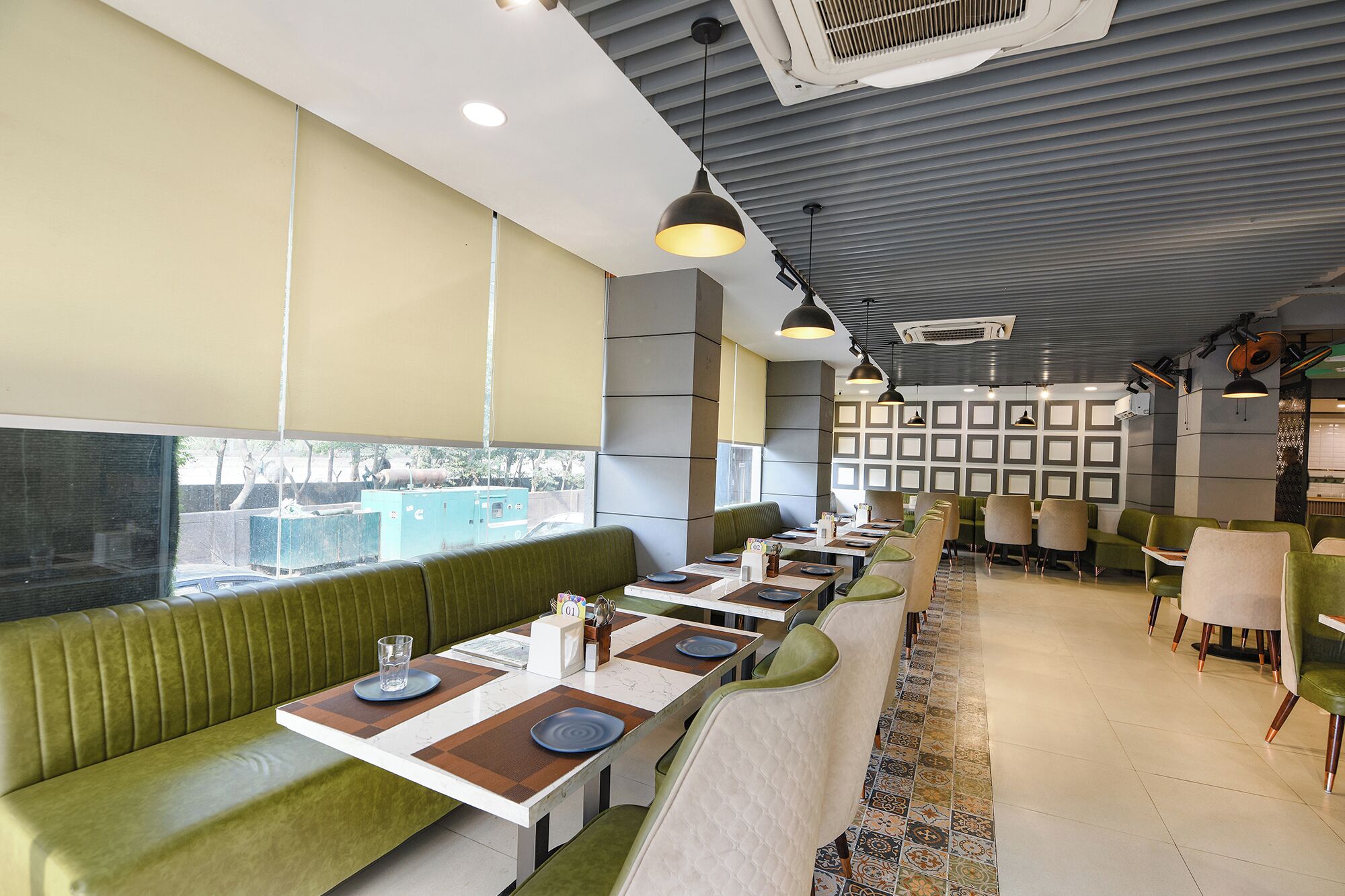 Een restaurant met groene bankjes en tafels, een patroon vloer en uitzicht door het raam.