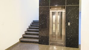 Eine Treppe führt zu einem Aufzug in einem Gebäude mit schwarzen Marmorwänden und einem polierten Granitboden.