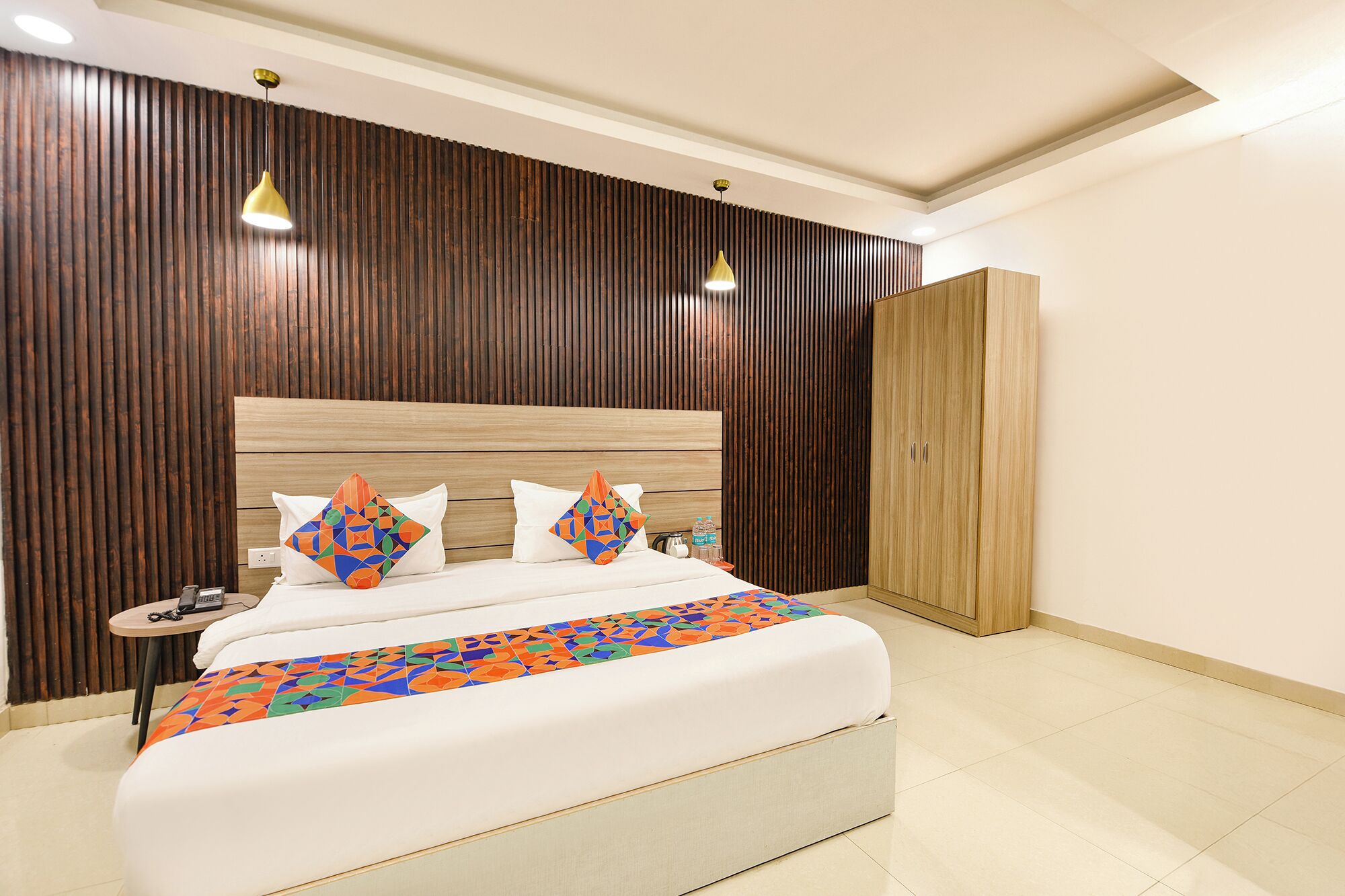 A modern bedroom with a large bed, wooden headboard, and a wardrobe.