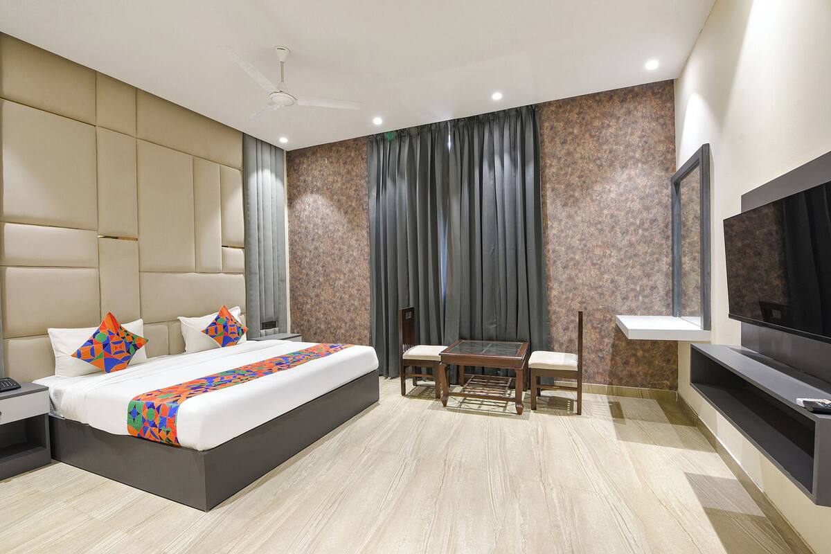Ein modernes Hotelzimmer mit einem großen Bett, einem Schreibtisch, einem Sessel, einem Fernseher und einem Deckenventilator.