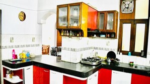 A kitchen with a gas stove, cabinets, and a clock on the wall. - Fabhotel Noida Dreamz (Noida)
