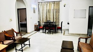 A spacious living room with a dining area, featuring a large table and multiple chairs, a sofa, and a coffee table. - Fabhotel Noida Dreamz (Noida)