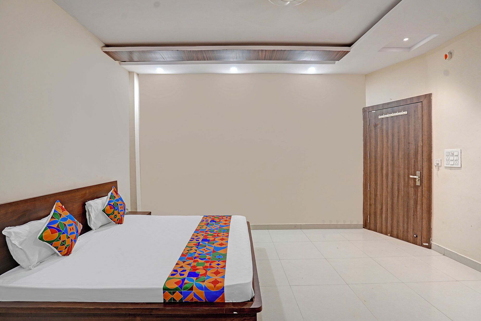Una habitación de hotel con una cama, un armario de madera y suelo de baldosas.