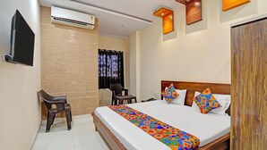 A hotel room with a bed, a desk, a chair, an air conditioning unit, and a wardrobe. - Fabhotel Paras Palace (Bhopal)