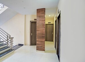 A modern hotel hallway with a staircase on the left, two wooden doors labeled "Room No. 308" and "Room No. 309", and a metal railing. - Fabhotel Paras Palace (Bhopal)