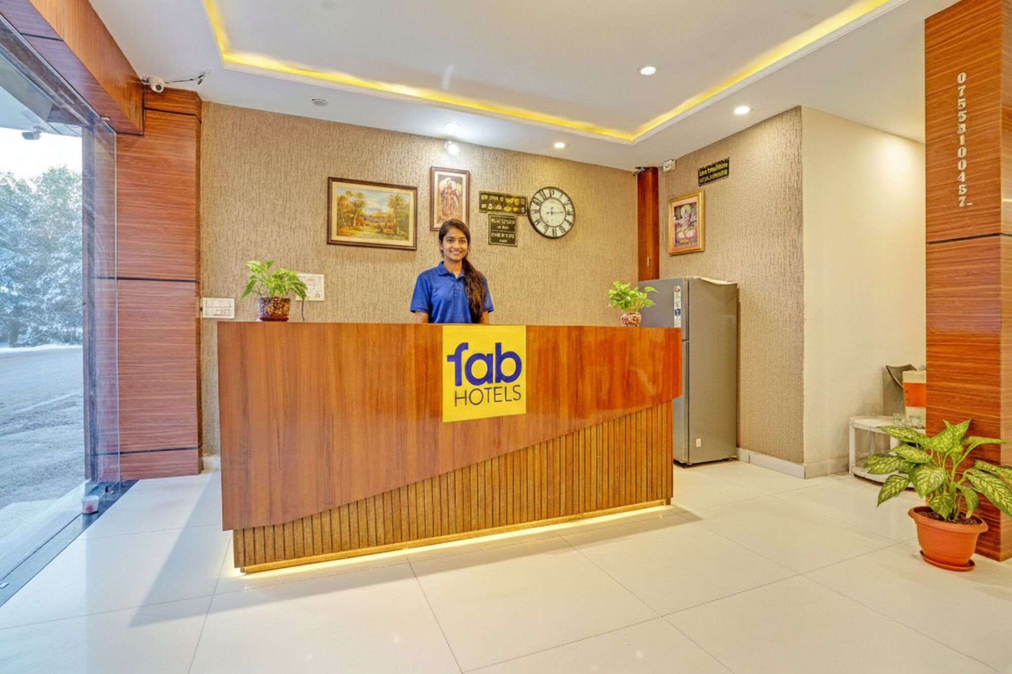 A reception desk with a wooden finish, a clock, and framed pictures on the wall.