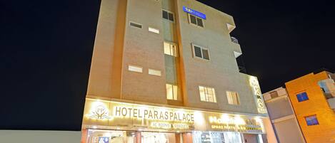 Un hotel llamado 'Hotel Paras Palace' con un letrero que indica 'Habitaciones con aire acondicionado y salón de banquetes'.