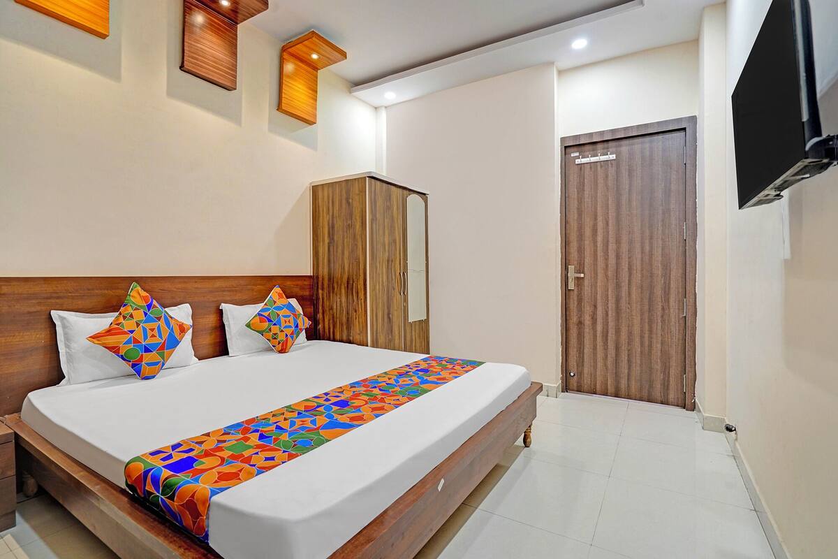 Cama bem arrumada com um corredor de cama de padrão geométrico colorido, uma cabeceira de madeira e duas almofadas com padrões geométricos.