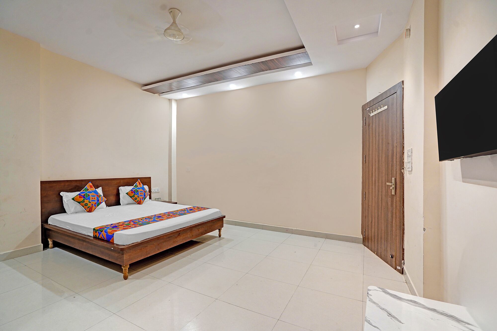 A bedroom with a wooden bed, white bedding, and colorful pillows.