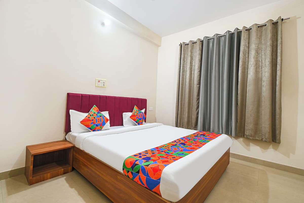 A neatly made bed with a patterned bedspread, a wooden nightstand, and a headboard.