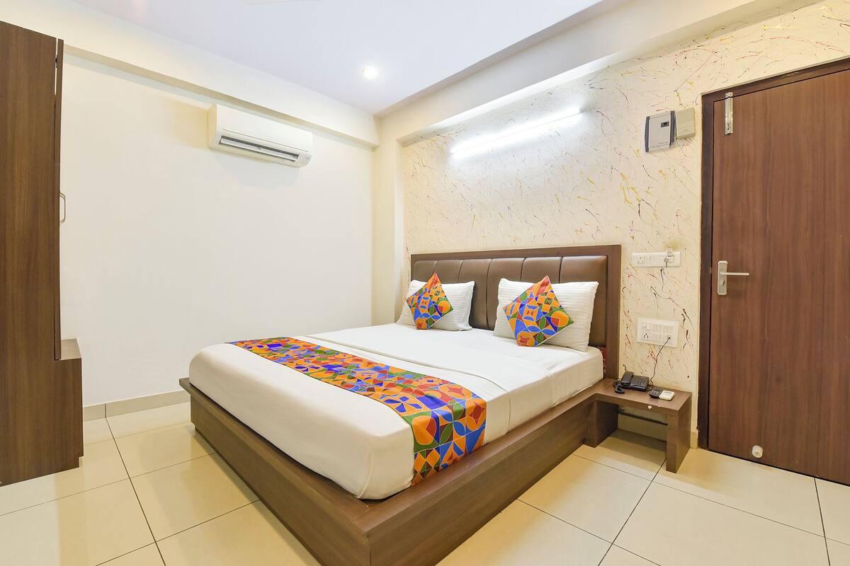 Une chambre d’hôtel avec un lit, une table de chevet, un appareil de climatisation et une porte.