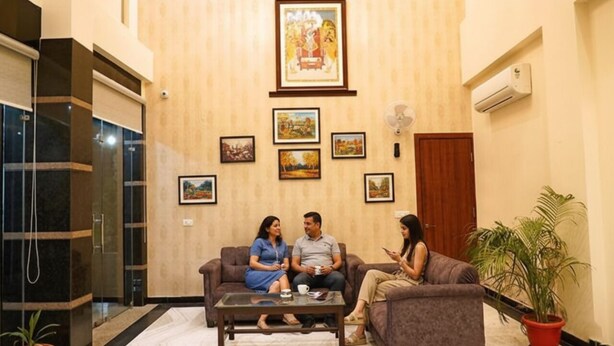 A lobby with a reception desk, a large framed picture above the counter, and a seating area with a coffee table. - Fabhotel The Grand Manmuralidhar (Jaipur)