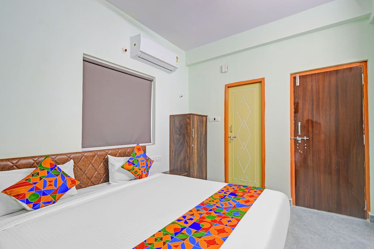 Ein Hotelzimmer mit einem Bett, zwei Türen, einer Klimaanlage und einem Fenster.